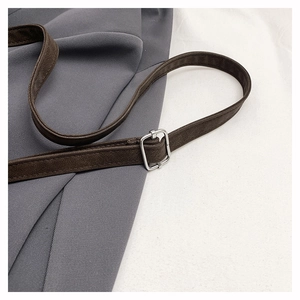 Détail d'une bandoulière en cuir marron avec boucle en métal argenté et couture