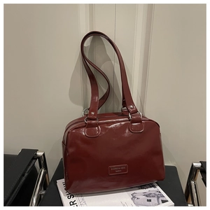 Detail view of deep red glossy shoulder bag with silver rings and brand patch