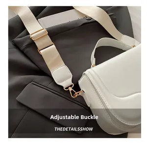 Detail of adjustable woven strap and gold buckle on a white saddle crossbody bag