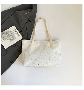 Vue à plat d'un sac cabas crème à motifs d'étoiles grises à côté d'un blazer gris