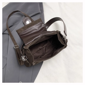 Détail d'un sac vintage marron foncé avec rabat magnétique et bandoulière réglable