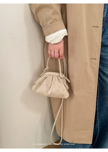 Dettaglio borsa a secchiello plissettata beige con manico sottile e tracolla