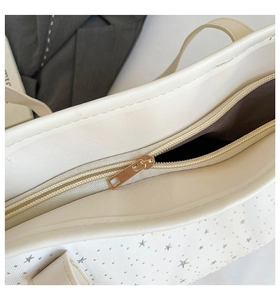 Détail du sac cabas blanc avec fermeture éclair dorée et clous étoiles argentés sur similicuir