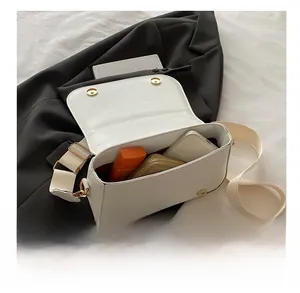 Detail view of the spacious white leather handbag interior with wide canvas shoulder strap