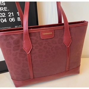 Close-up of wine red leopard print tote bag featuring a gold Fashion & Bags logo plate