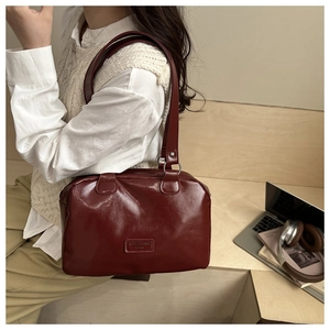 Vue détaillée du sac à bandoulière bordeaux en cuir brillant porté par un modèle