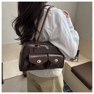 Detail der dunkelbraunen, glänzenden Ledertasche mit goldenen Drehverschlüssen im Retro-Stil