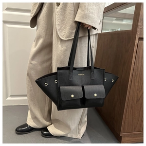 Detail of black lychee texture tote bag with golden button pockets and side eyelets