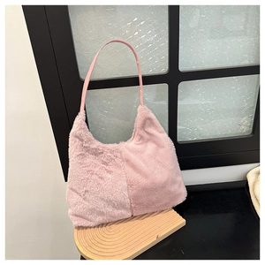 Dettaglio di una borsa a tracolla in morbido peluche rosa su un vassoio di legno