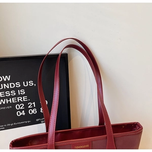 Close-up of wine red tote bag featuring gold embossed text and fine leather texture