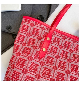Close-up of red jacquard pattern on a tote bag with leather handle and gold rivet details