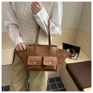 Close-up of brown faux leather tote with litchi texture and golden metal hardware