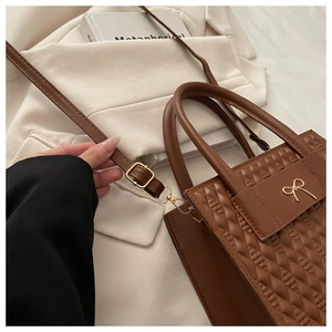 Dettaglio borsa a tracolla marrone vintage con fiocco dorato e trama in pelle
