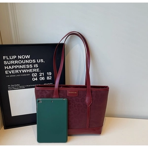 Detail of burgundy leopard print leather tote bag with gold logo and green tablet