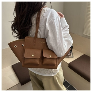 Détail du sac cabas en cuir grainé marron avec deux poches frontales et boucles dorées