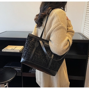 Detail of leopard print tote bag featuring black leather handles and fashion logo plaque
