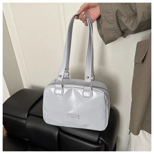 Detail of light blue glossy leather handbag featuring metallic brand logo and slim straps
