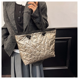 Détail du sac cabas matelassé doré avec motifs d'étoiles et poignées en corde noire épaisse