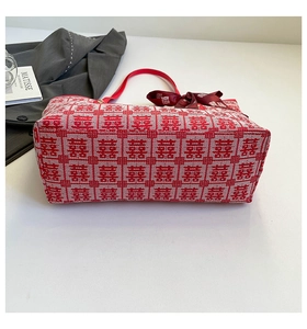 Detail of red festive tote bag featuring Xi character pattern and bow ribbon decoration