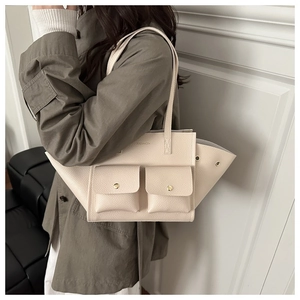 Dettaglio della borsa tote in pelle color panna con doppie tasche e fibbie dorate