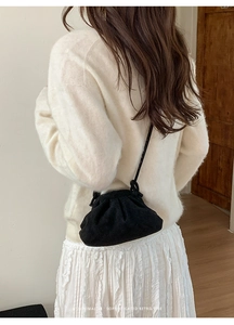 Borsa a nuvola nera a pieghe minimalista indossata su un maglione di maglia bianca