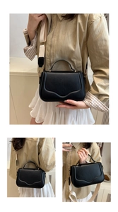 Detailed view of black matte leather handbag featuring adjustable wide fabric shoulder strap