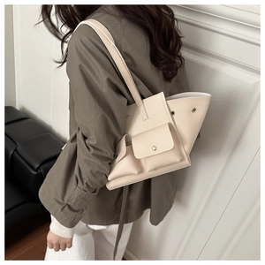 Dettaglio borsa tote color crema con tasche multiple e bottoni a pressione dorati