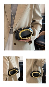 Fashionable black glossy oval crossbody bag with large gold metal frame and chain strap