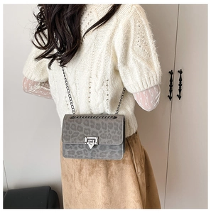 Detail of grey leopard print crossbody bag with silver chain strap on knit sweater