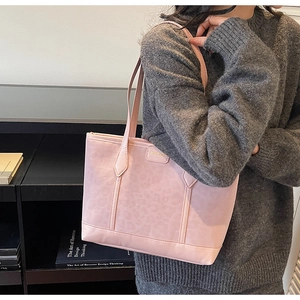 Detail of pink leopard pattern tote bag with metal logo worn on model's shoulder