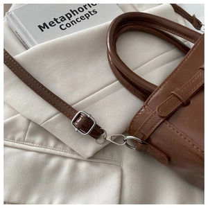 Close-up of brown oiled leather shoulder bag with silver hardware and fine stitching detail
