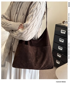 Detailed texture of a large brown suede tote bag featuring a front pocket design