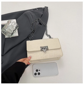 Detail view of cream chain bag with metal lock and phone for size reference