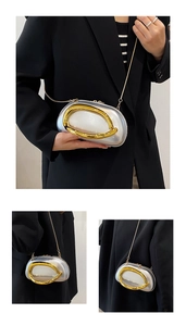 Close-up of silver luxury handbag with oversized gold ring handle and metal chain strap