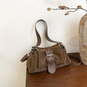 Sac baguette en daim marron avec boucle en métal sur une table en bois style rétro