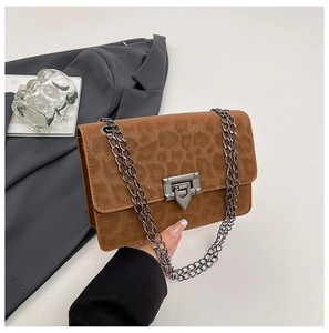 Close-up of leopard print suede crossbody bag featuring dark metal chain and twist lock