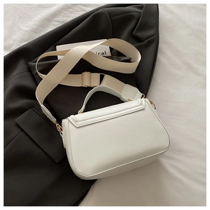 Detail of white leather handbag with adjustable wide fabric strap and gold hardware