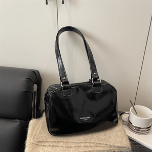 Chic black patent leather handbag with glossy finish and thin shoulder straps on knit fabric