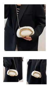 Detailed view of white crossbody bag with glossy finish and large gold oval metal ring