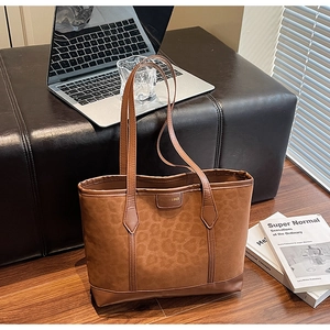 Close-up of leopard print tote bag with brown leather handles and brand logo tag