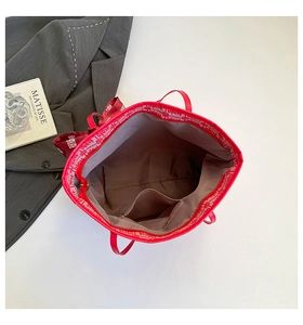 Interior view of red tote bag showing brown fabric lining and secure zipper pocket detail