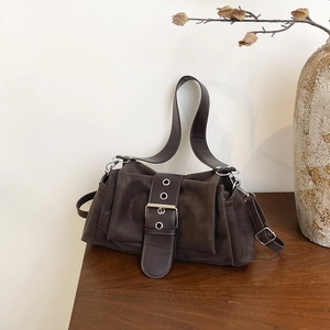 Sac baguette rétro marron foncé avec boucle métallique sur une table en bois rustique