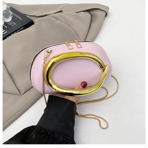 Detail view of pink semi-circle crossbody bag with gold C-shaped handle and chain