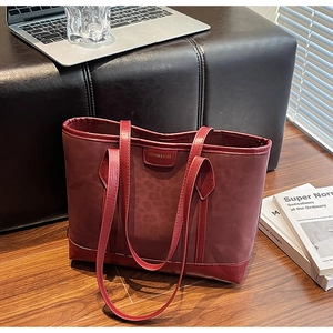 Detail of burgundy tote bag with faux leather panel and FASHION & BAGS logo patch
