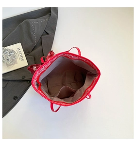 Fashionable red tote bag with festive ribbon bow and internal zipper pocket detail