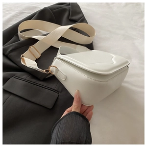 Close-up of white leather shoulder bag with wide nylon strap and gold hardware accents