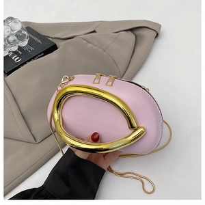 Macro detail of pink leather handbag featuring a large gold horseshoe handle and chain strap