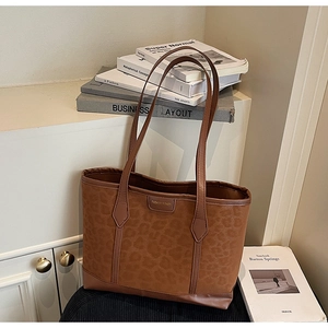 Close-up of leopard print tote bag with brown leather trim on an aesthetic background