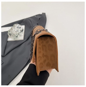 Detail view of brown suede crossbody bag with thick gunmetal chain strap and matte finish