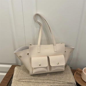 Creamy white pebbled leather tote bag with double front pockets on a soft knit blanket